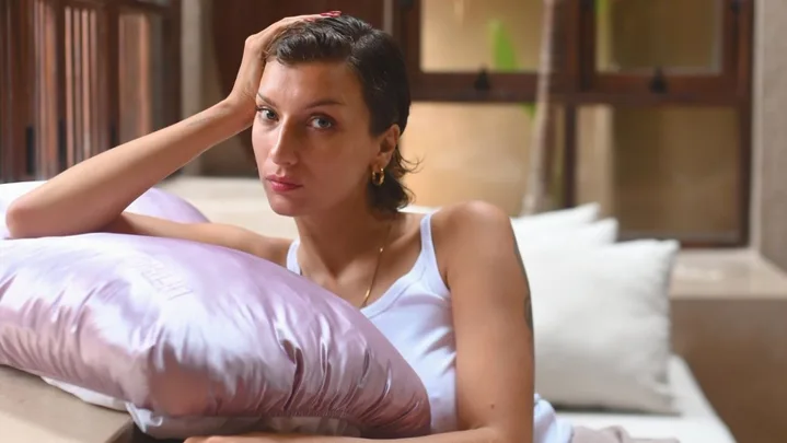 Woman leans on pink pillow