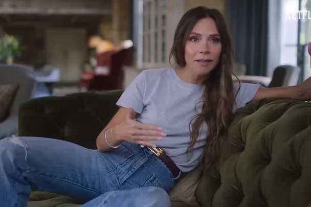 Victoria Beckham sits on a sofa