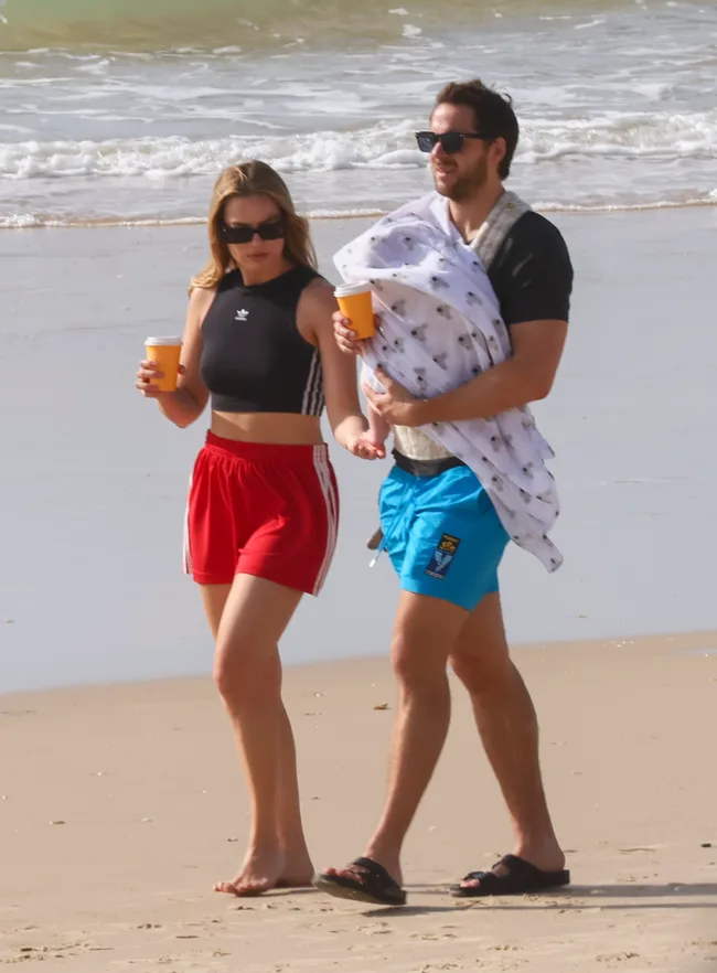 Margot Robbie and Tom Ackerley walking on the beach with their new baby.