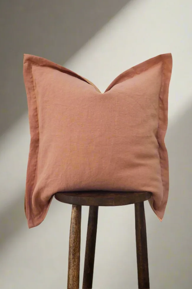 TSL Co orange linen pillow sitting upright on a wooden stool