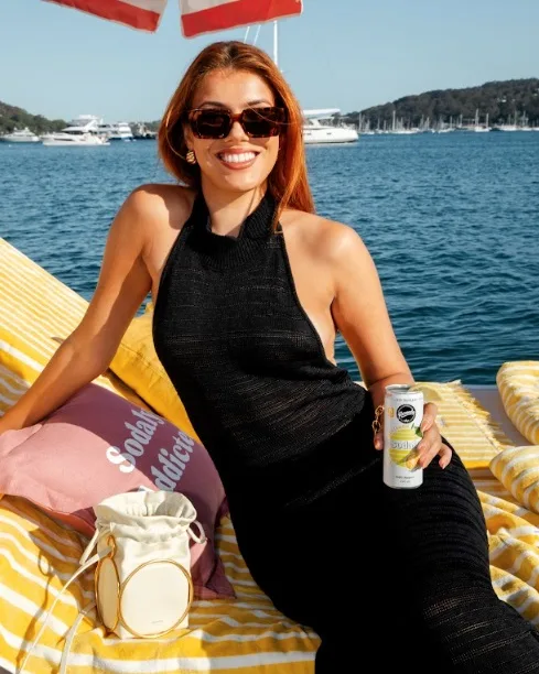 Woman in a black dress holds soft drink