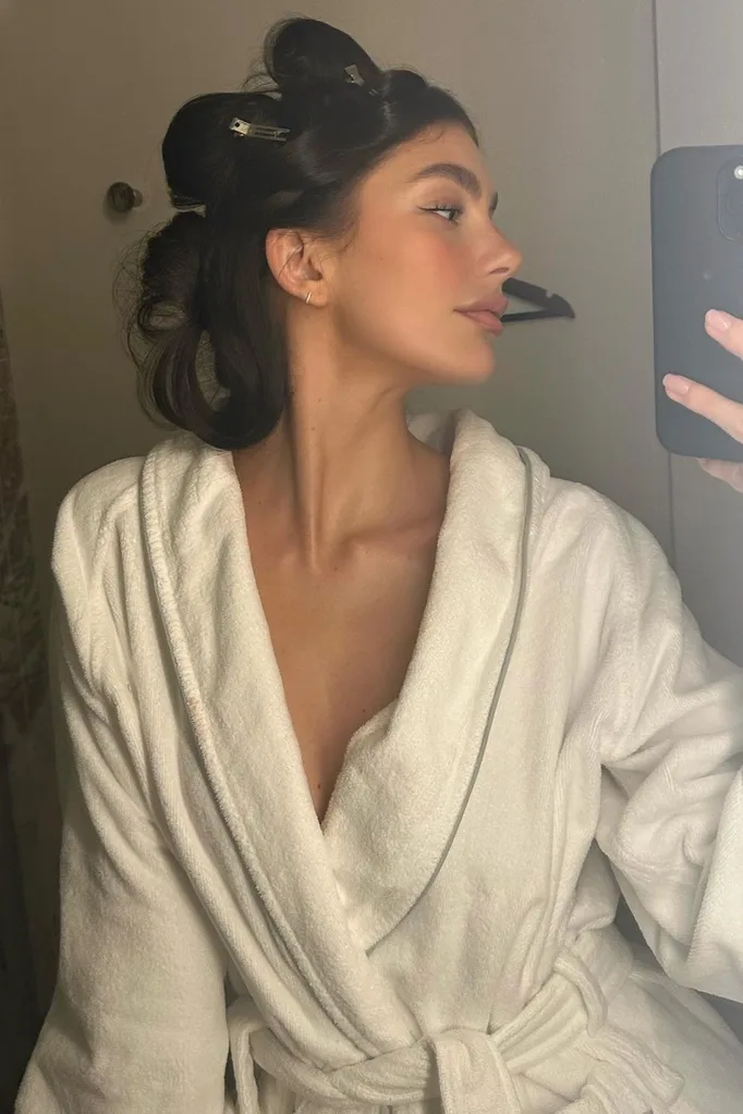 Woman posing in mirror with hair rollers in.