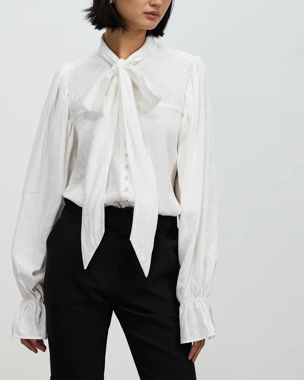 White pussy bow blouse on a model.