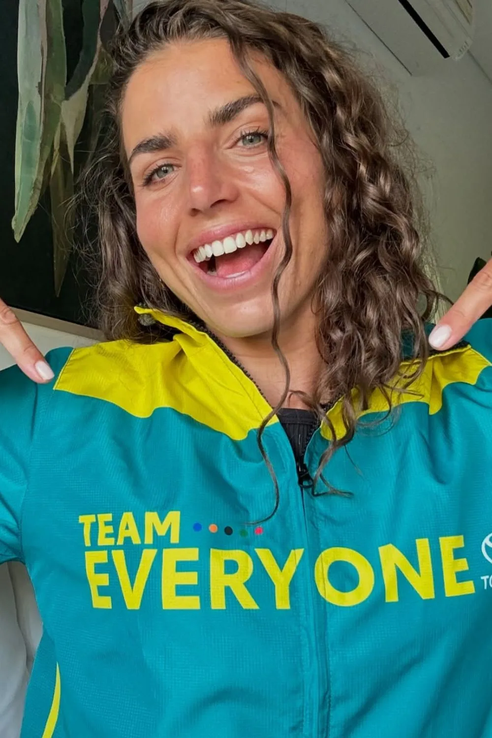 Jess Fox wearing a green and gold jacket with the words "Team Everyone" printed on the front.