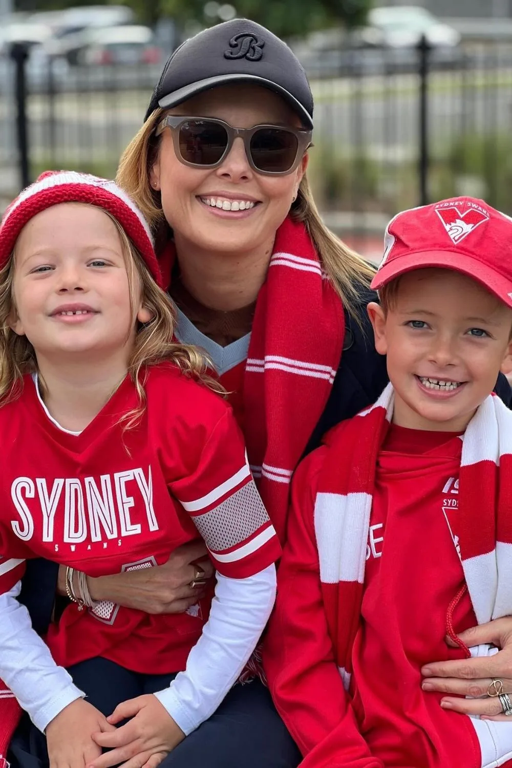 Journalist Ally Langdon with her to young children smiling in Sydney Swans merchandise