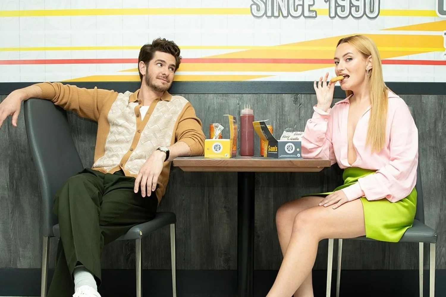 Andrew Garfield looking at Amelia Dimoldenberg lovingly while she eats a nugget on set of Chicken Shop Date