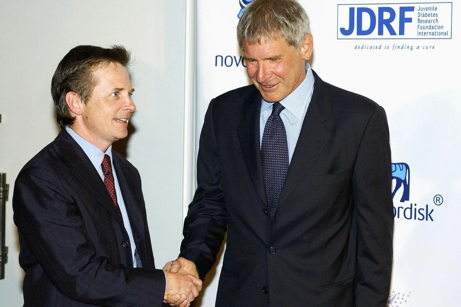 Michael J. Fox shaking hands with Harrison Ford