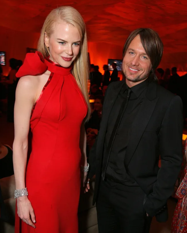 nicole kidman and keith urban at their first oscars as a couple with nicole wearing a bright red dress tied at the neck with a large bow