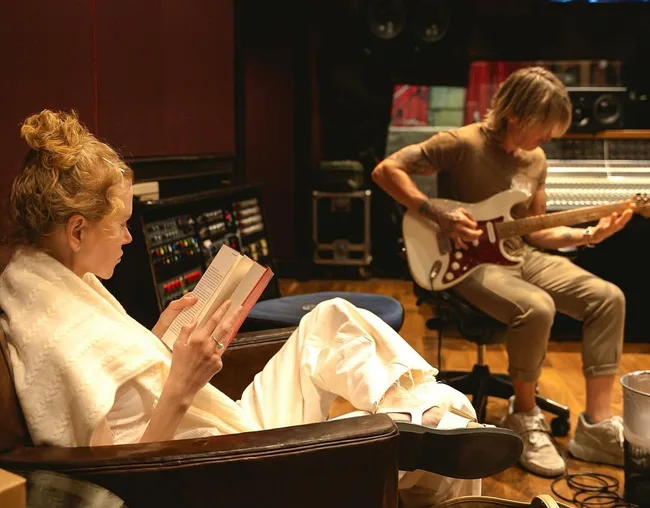 nicole kidman and keith urban in the recording studio. Nicole reads a book while Keith plays guitar