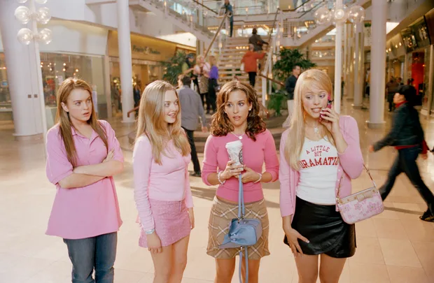 Four girls standing in a shopping mall wearing pink.