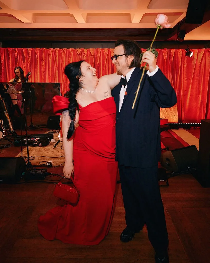 lena dunham and husband luis felber embrace behind the scenes of the too much premiere as Luis holds a long stemmed red rose