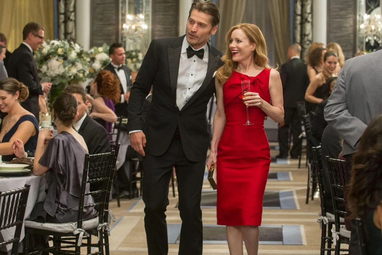 Woman in red dress walking with a man in a tuxedo.
