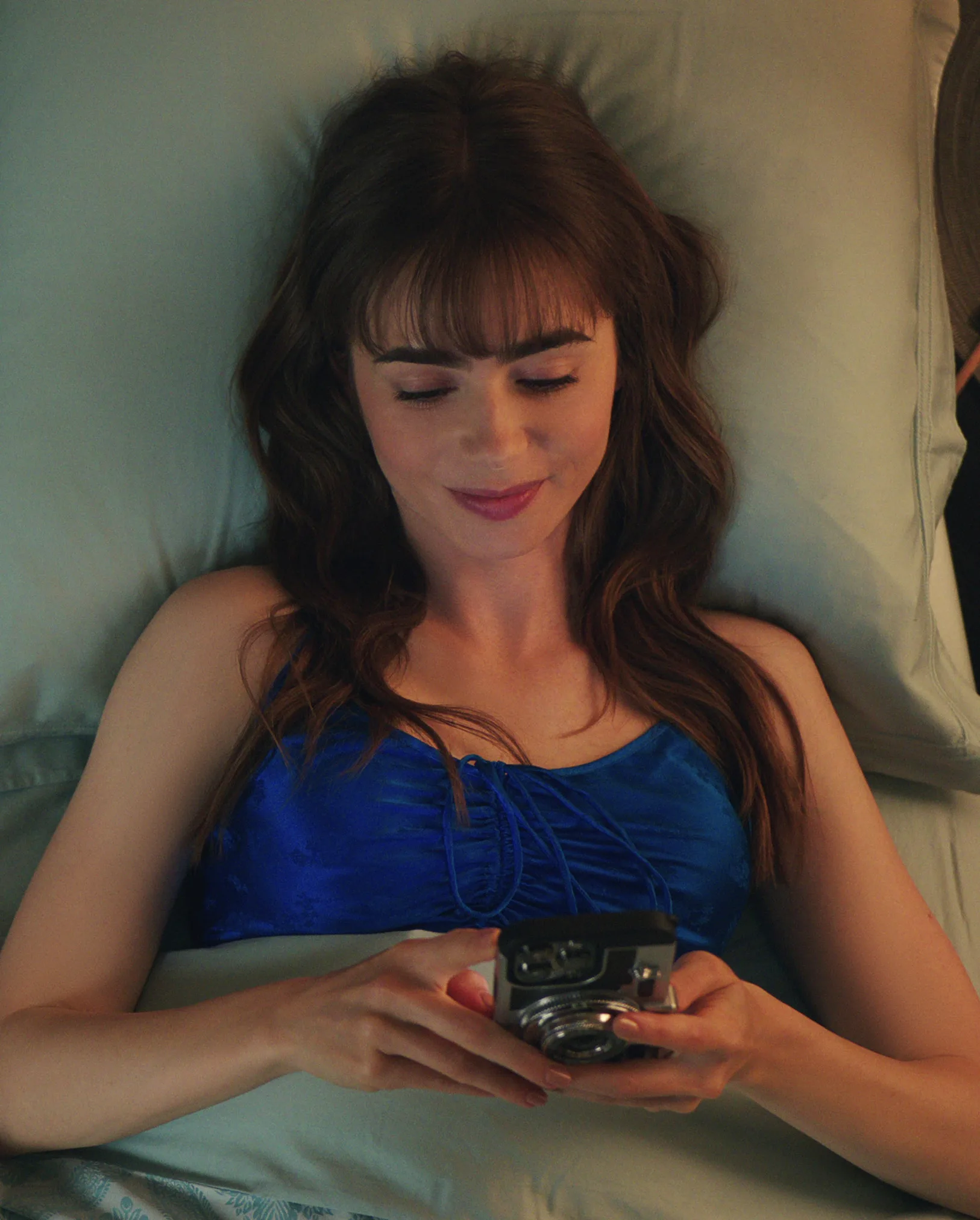 Woman in bed smiling at her phone. Not using ChatGPT for therapy. 
