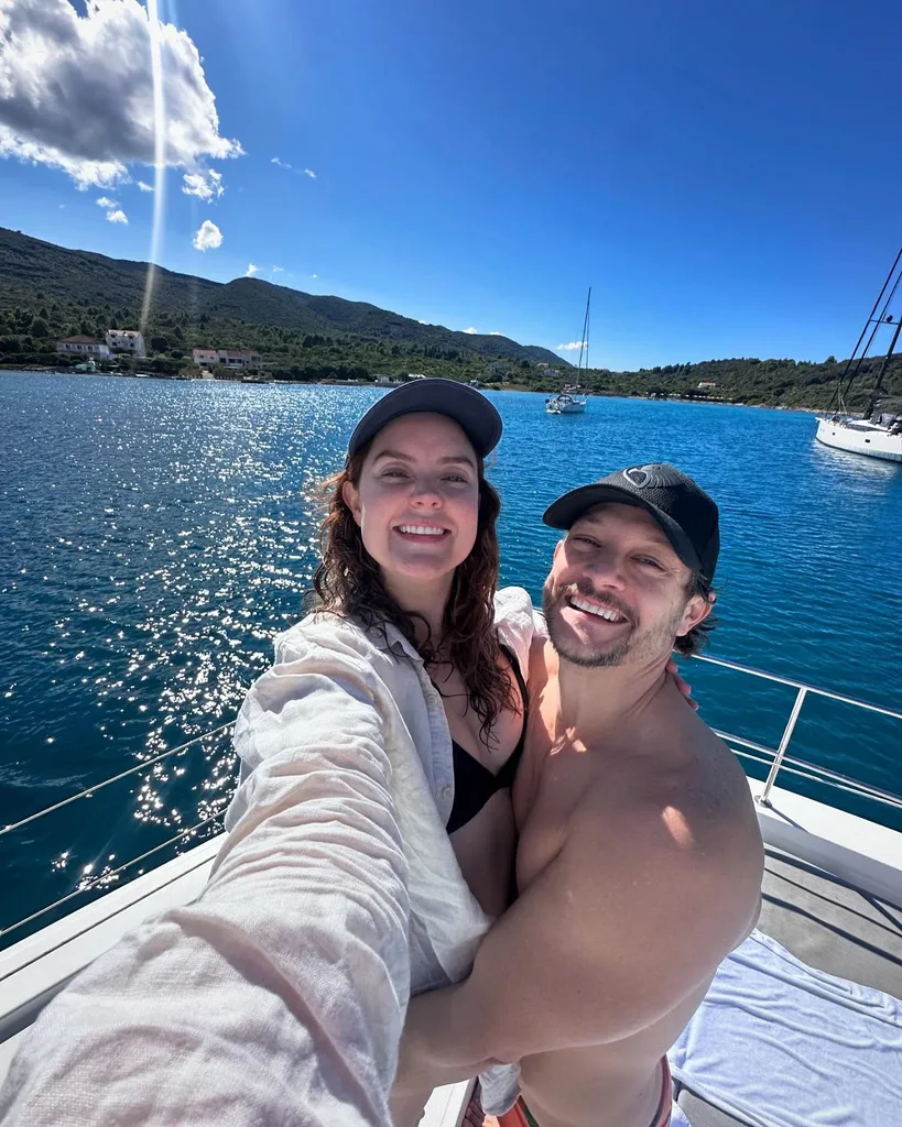 rob mills and georgie tunny smiling for a selfie on a boat with blue water