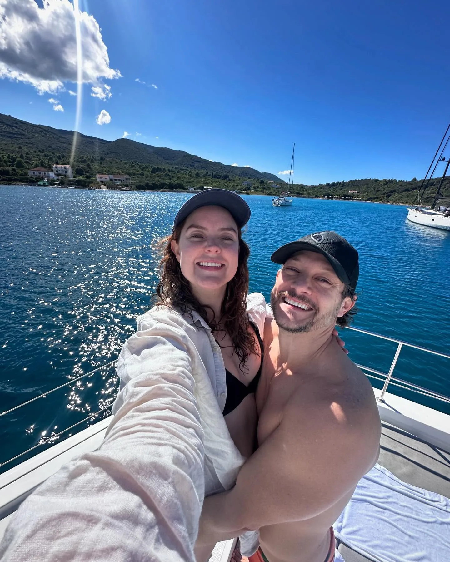 rob mills and georgie tunny smiling for a selfie on a boat with blue water
