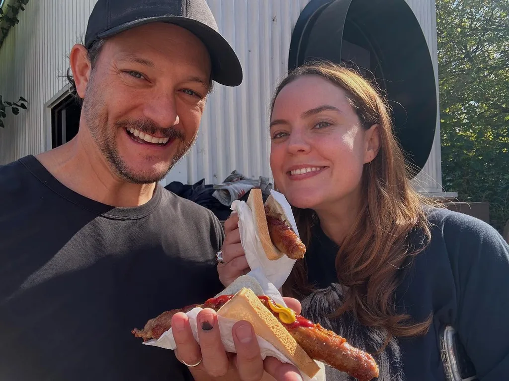 rob mills and geogie tunny smiling with a sausage sandwhich