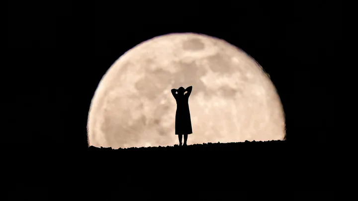Woman in front of full moon