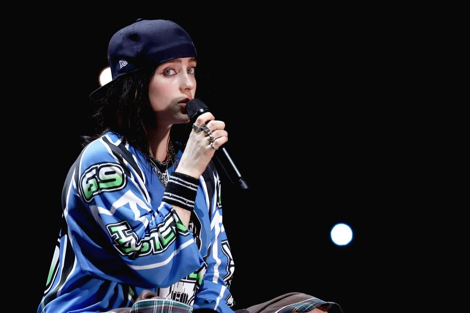 billie eilish on stage singing against a dark background