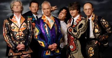 split enz band posing together in detailed coulourful suits