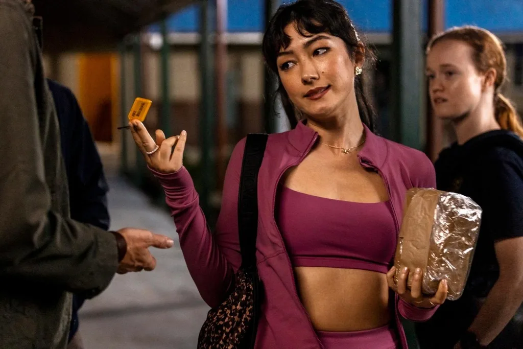 a girl in pink activewear handing back a key while holding a block of clay for a scene in he had it coming