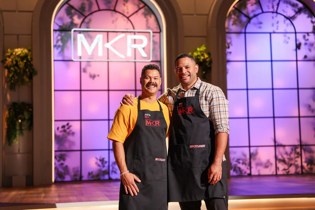two men posing together in aprons in front of large wondows