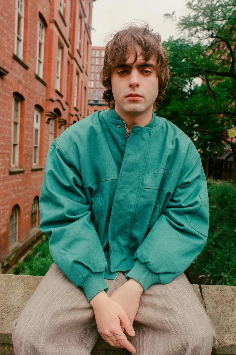 lennon gallagher posing while sitting on a wall