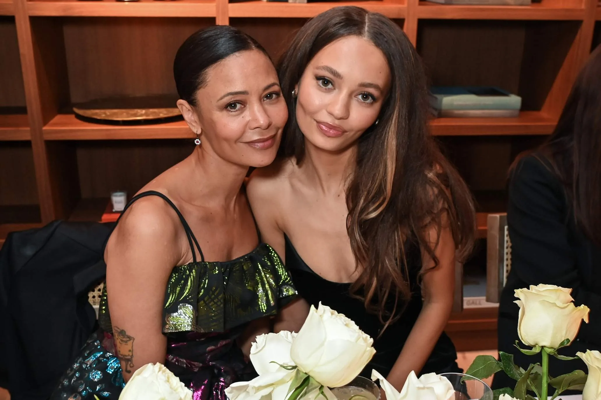 nico parker and thandiwe newton posing while sitting at a table for an event
