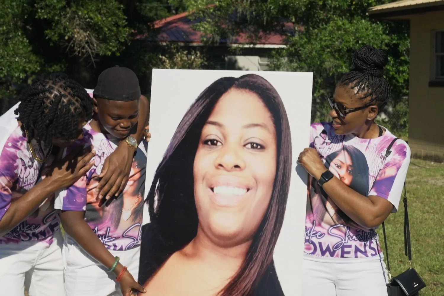 Ajike's children crying while holding a picture of their mother.