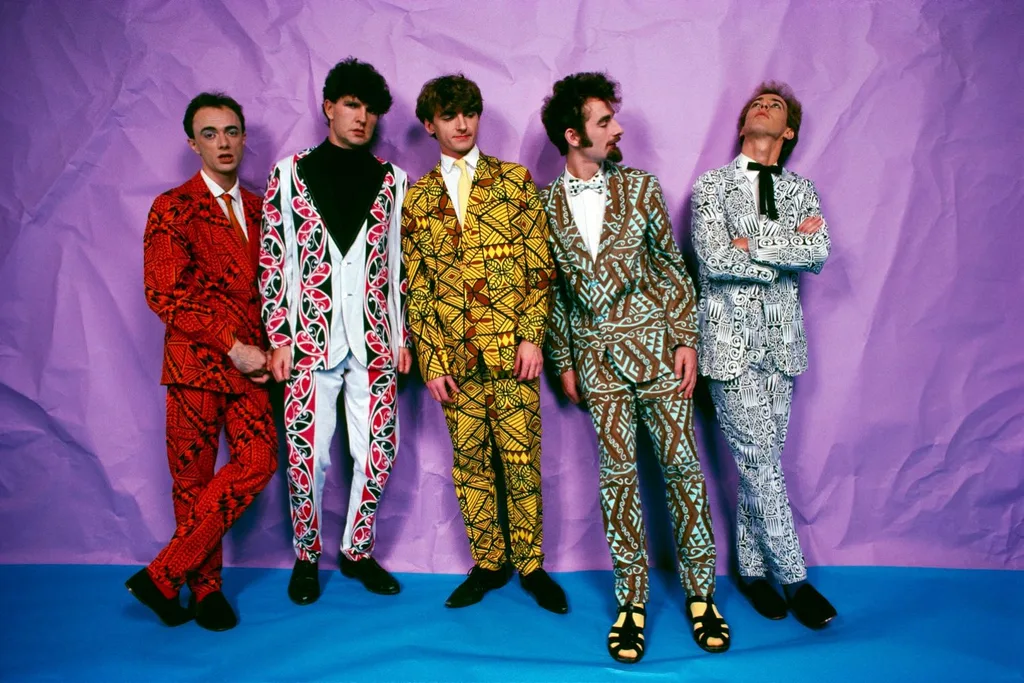 split enz members in brightly coloured suits against a bright purple backdrop