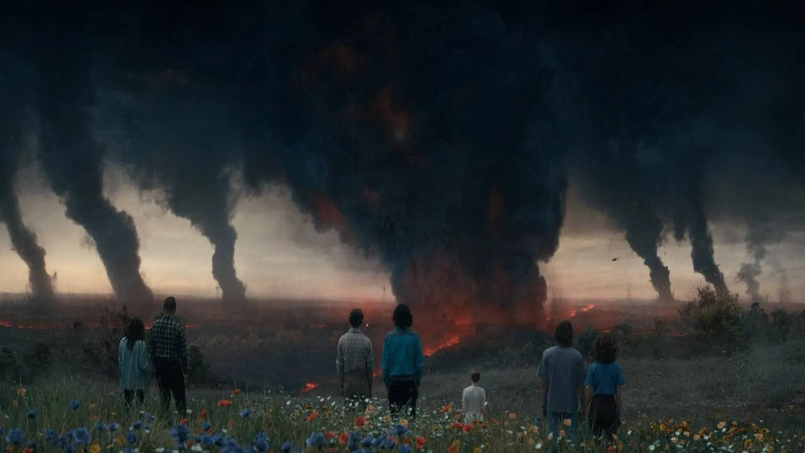 black smoke patches coming from the town of hawkins, view from a hill as the group look on