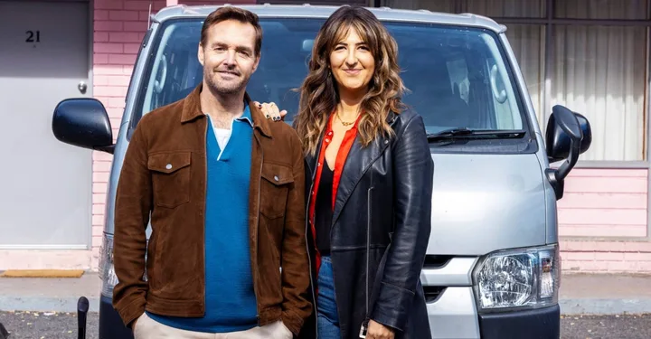 a man and woman pose in front of a silver van