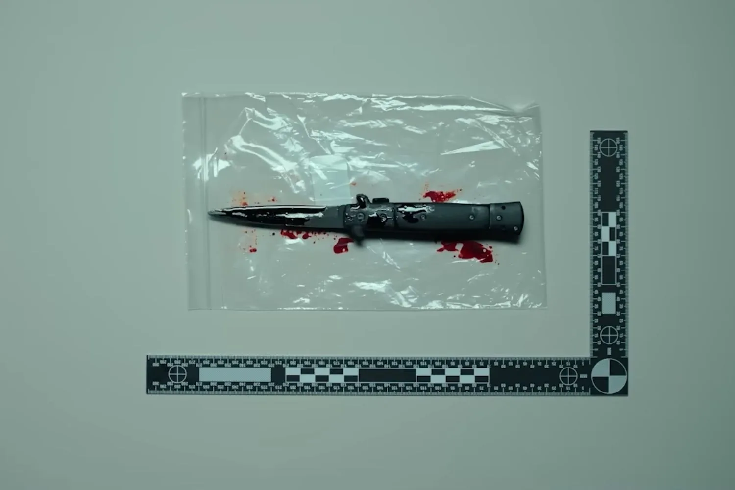 switchblade knife with blood in a clear plastic bag in a forensic photo