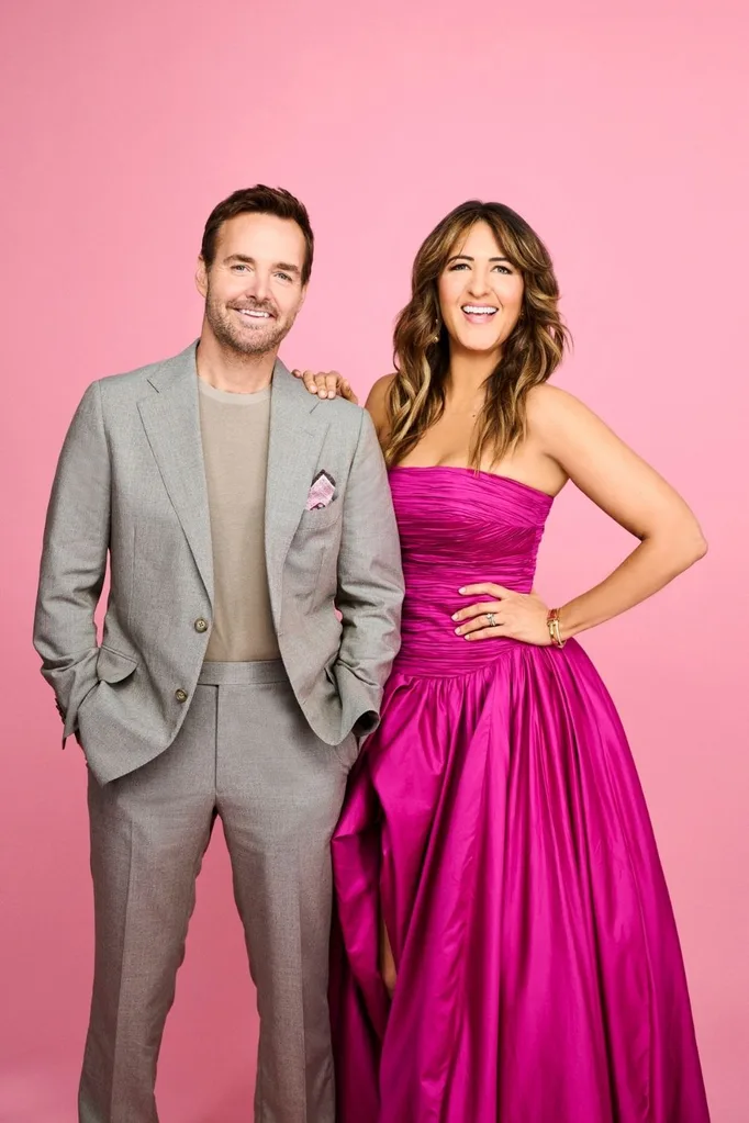 will forte and d'arcy carden pose for a photoshoot with pink backgroud, will in grey suit and d'arcy in pink dress, both smiling