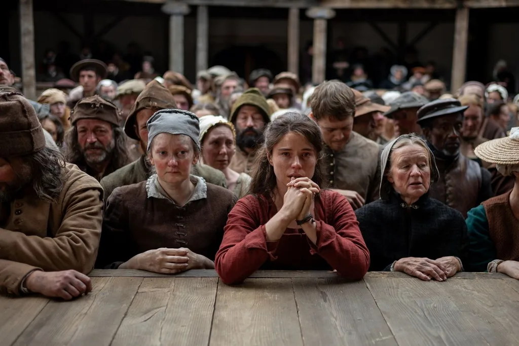 a crowd of people in period clothing watching a stage