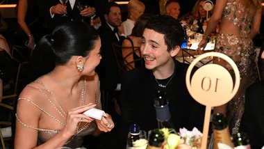 Kylie Jenner and Timothee Chalamet respond to name card at Golden Globes while seated at their tables.