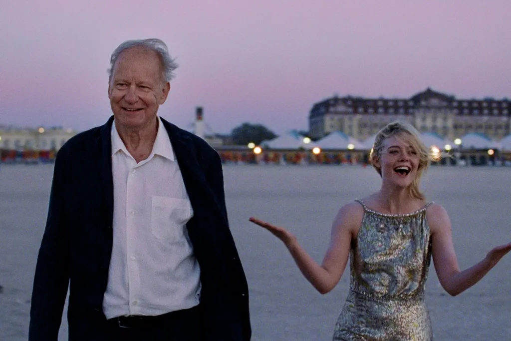 an older man and a young woman smiling on a beach at dusk