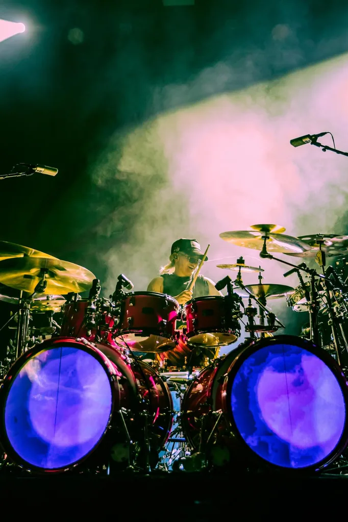 G flip drumming on stage wearing a cap.