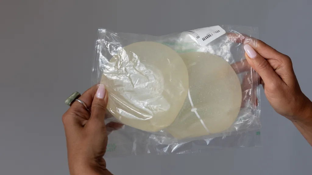 hands holding up a bag of removed breast implants
