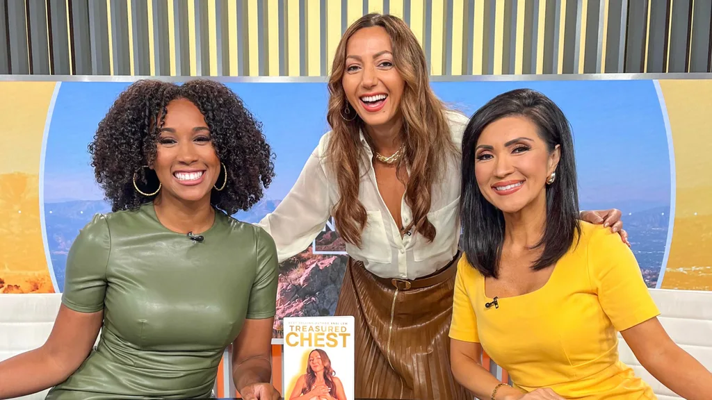 andi leaning down to pose for a photo with two news anchors after an appearance