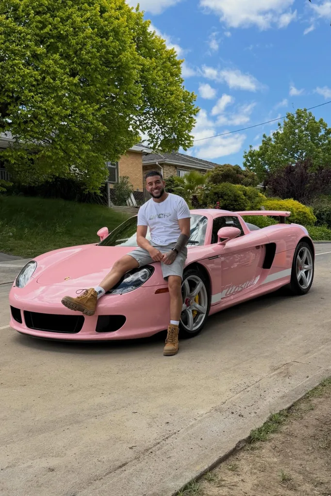 Adrian Portelli sitting on top of a pink Porche.