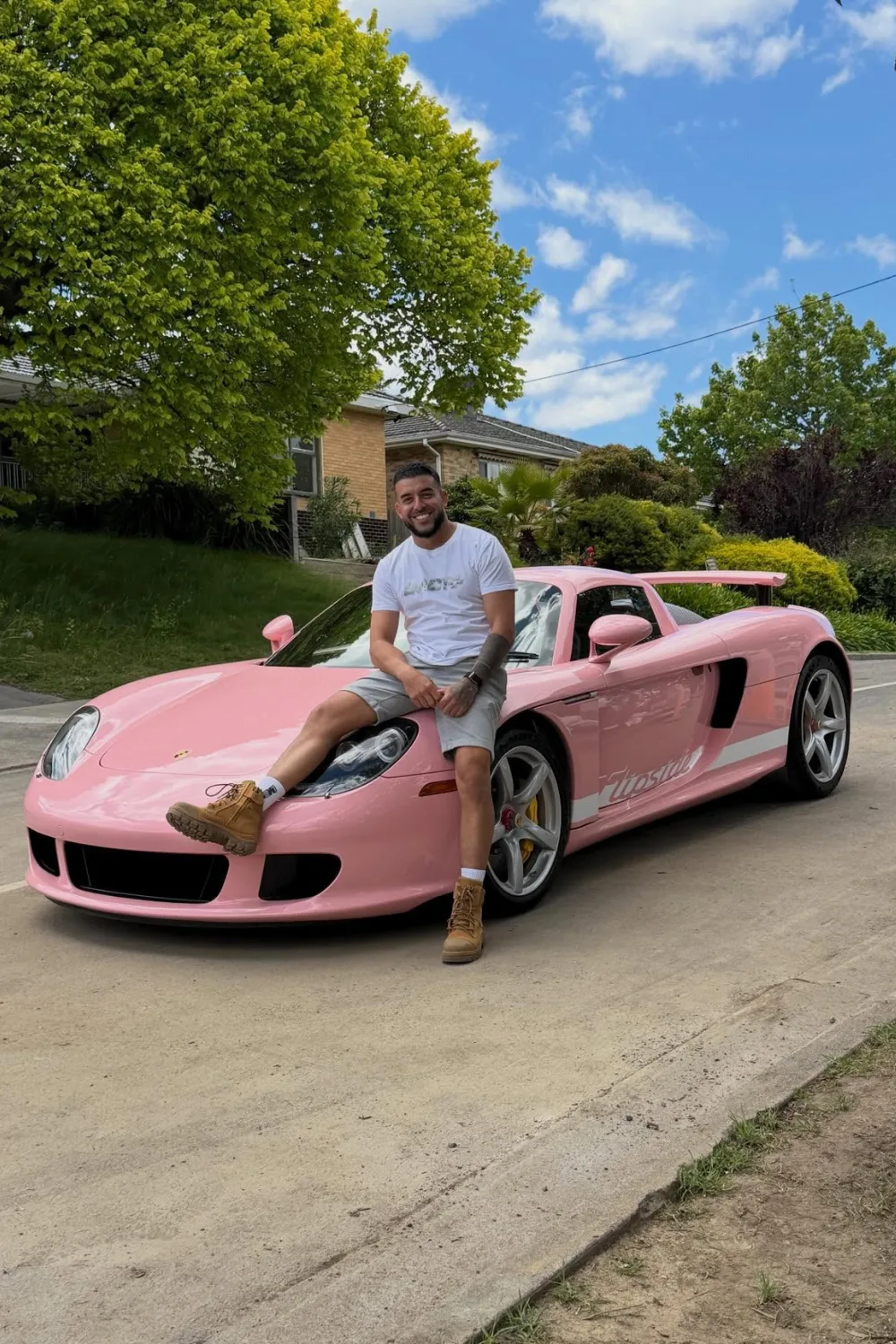 Adrian Portelli sitting on top of a pink Porche.