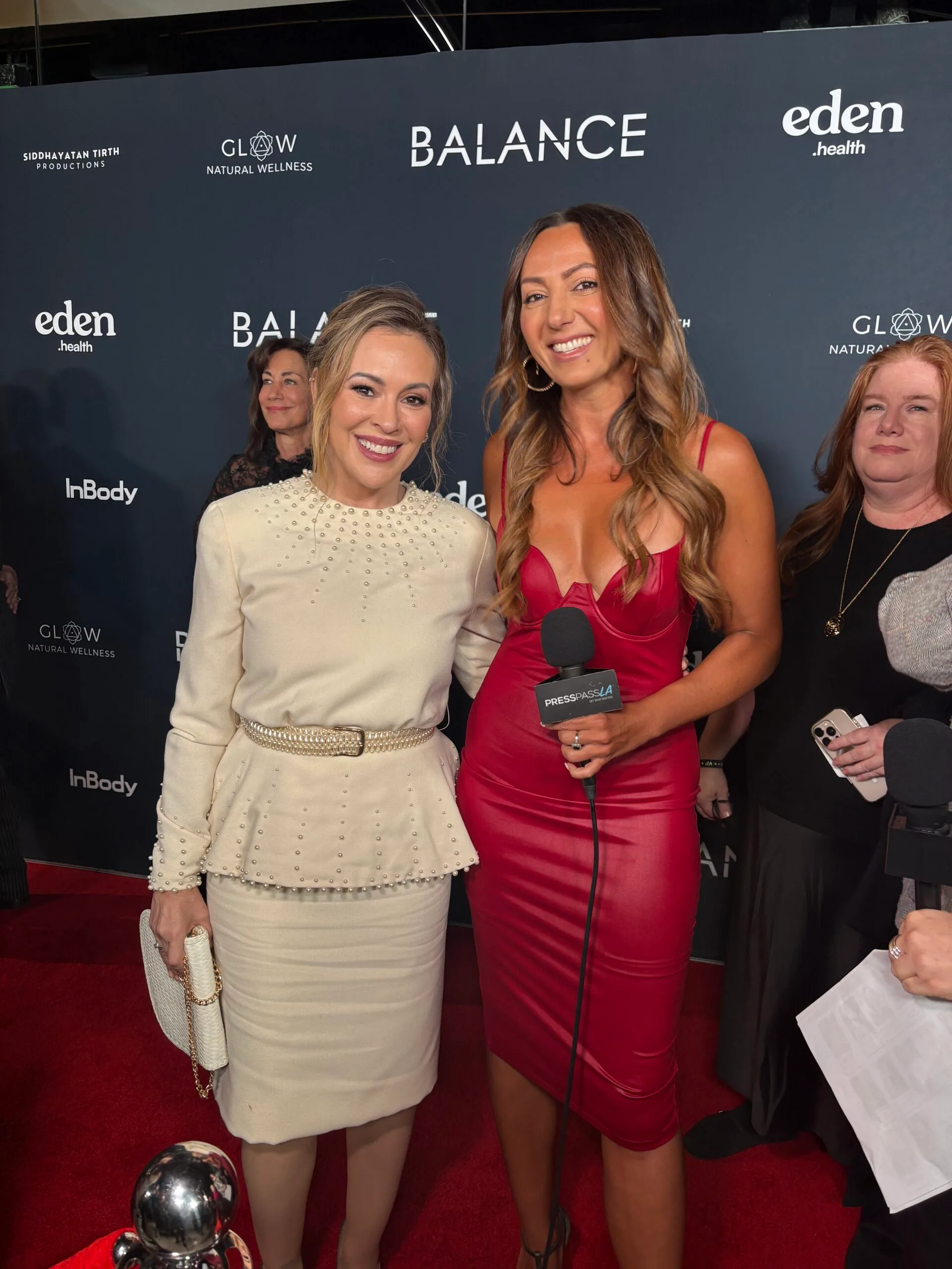 alyssa milano smiling for a photo next to andi lew in a red dress on the red carpet