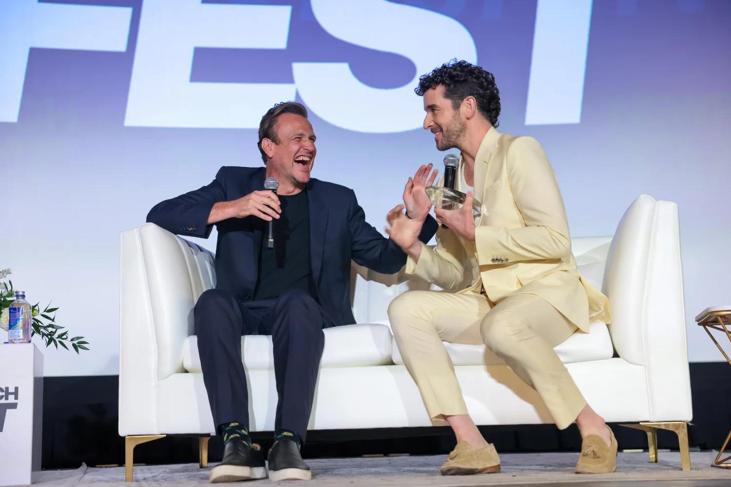Michael Urie and Jason Segel laughing at a press event. 