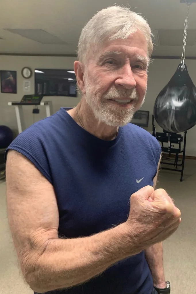 Chuck Norris flexing his bicep in a gym.