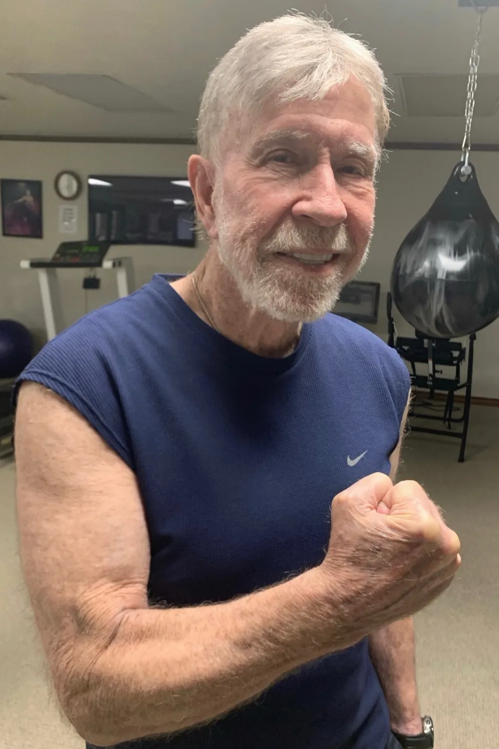 Chuck Norris flexing his bicep in a gym.