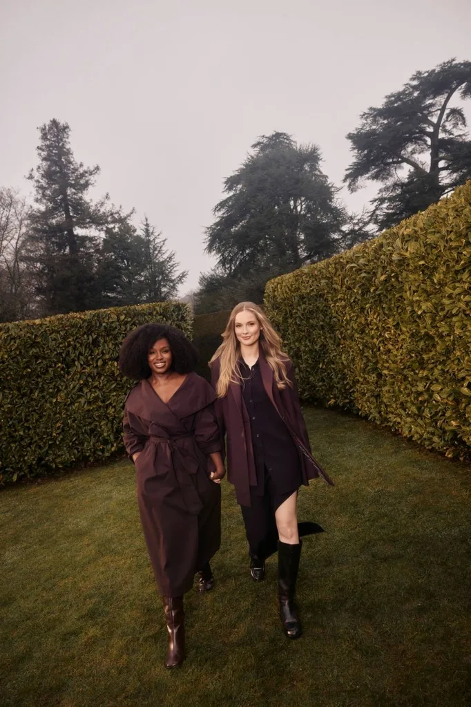 two women walk hand in hand through a garden