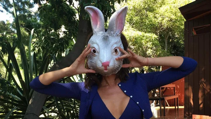 Victoria Beckham holding up a rabbit mask to her face.