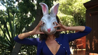 Victoria Beckham holding up a rabbit mask to her face.