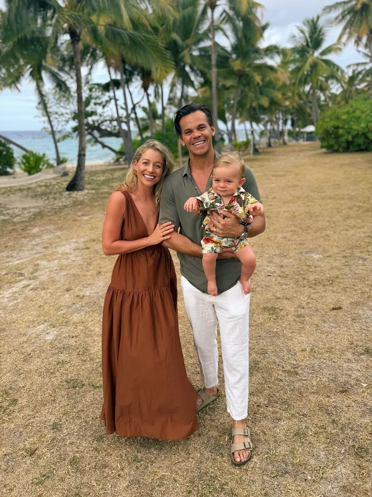 smiling holly kingston with her husband jimmy nicholson on a beach while smiling jimmy holds their baby son lennox