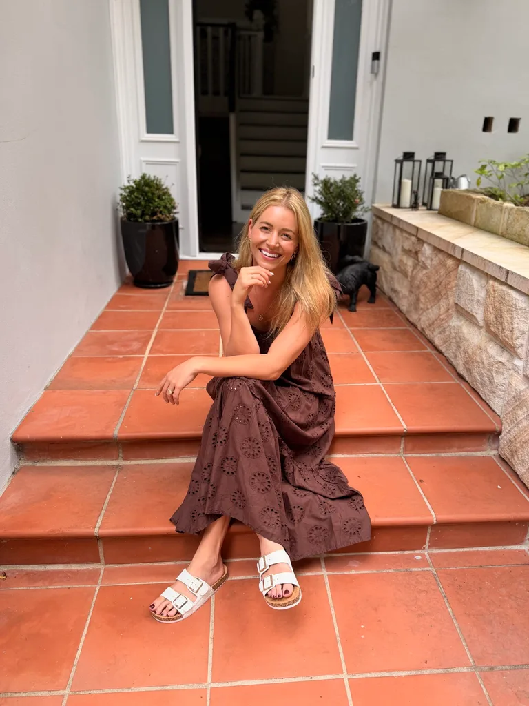 holly kingston sits on the steps of her house while smiling into the camera